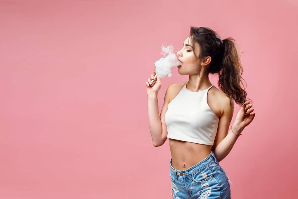 Casual,Pretty,Woman,Standing,And,Vaping,On,Pink,Background,In